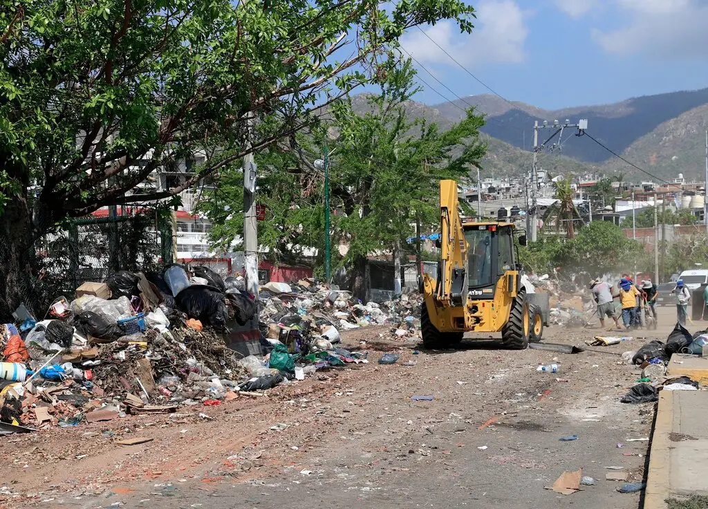Trabalhadores e uma máquina operam junto ao lixo empilhado pelas ruas de Acapulco