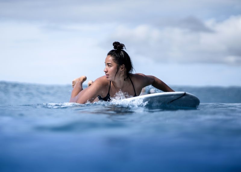 uma surfista olhando para o mar em busca da série de ondas certas