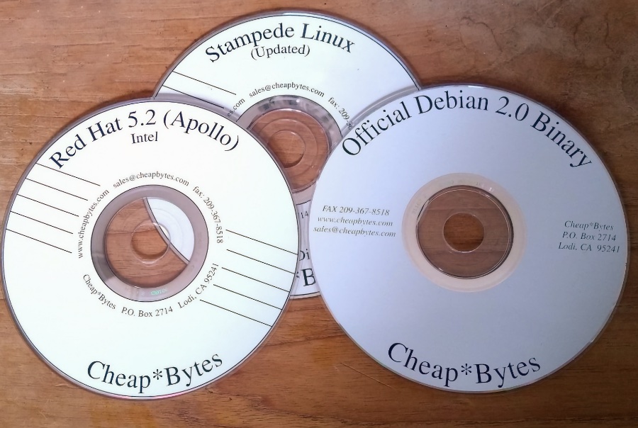3 CDs da Cheapbytes, com rótulos brancos, e títulos identificando Red Hat, Stampede Linux e Debian