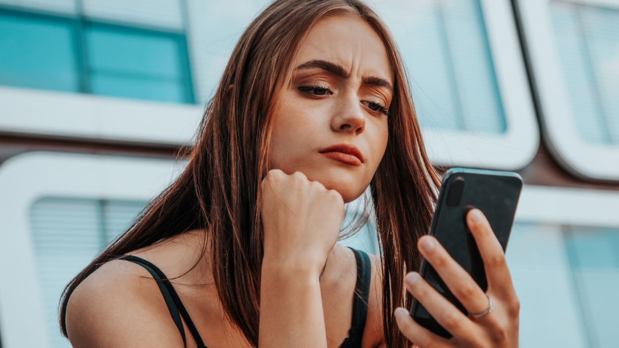 Uma moça olhando incrédula para o seu celular