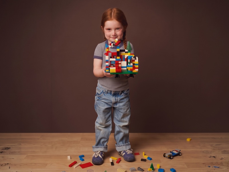 Uma menininha segurando sua criação original com Lego