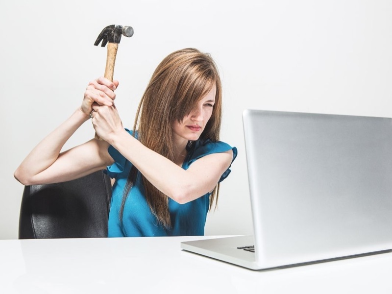 Mulher cansada se prepara para dar uma martelada na tela do computador